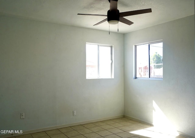 empty room with baseboards, a ceiling fan, and light tile patterned flooring