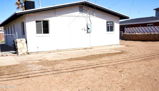 back of house with central AC, fence, and a chimney