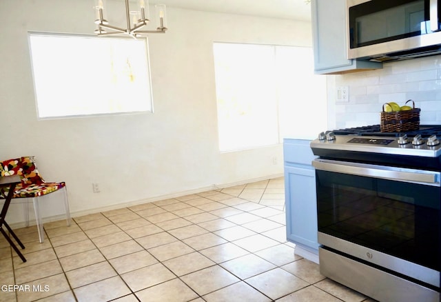 kitchen featuring a chandelier, backsplash, light tile patterned flooring, appliances with stainless steel finishes, and pendant lighting