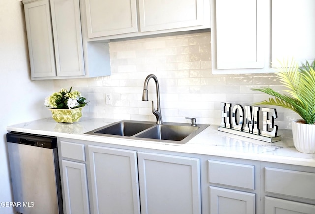 kitchen featuring tasteful backsplash, dishwasher, and a sink