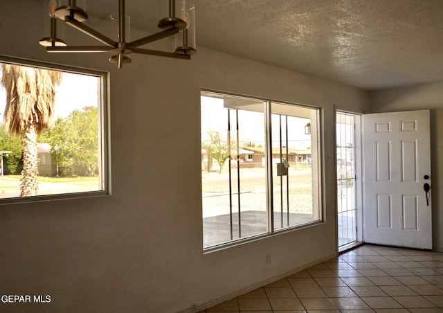 entryway with light tile patterned floors, a wealth of natural light, and a textured ceiling