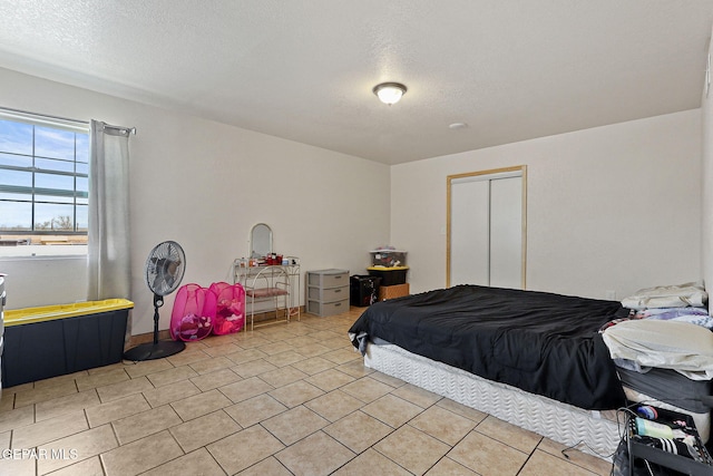 702 Thompson Rd, San Elizario, TX 79849 - bedroom with light tile patterned floors, a closet, and a textured ceiling