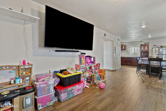 702 Thompson Rd, San Elizario, TX 79849 - recreation room with wood finish floors and a textured ceiling