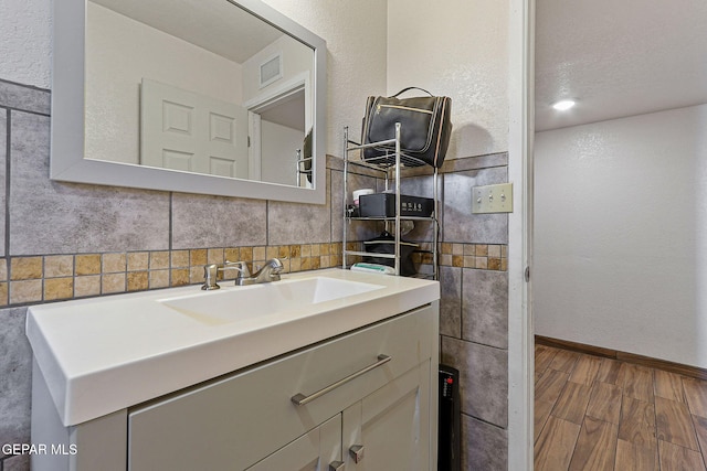 702 Thompson Rd, San Elizario, TX 79849 - bathroom featuring vanity, visible vents, wood finished floors, tile walls, and baseboards
