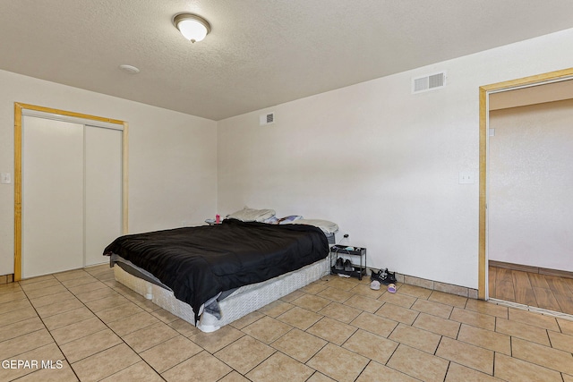 702 Thompson Rd, San Elizario, TX 79849 - bedroom featuring a closet, light tile patterned floors, visible vents, and a textured ceiling