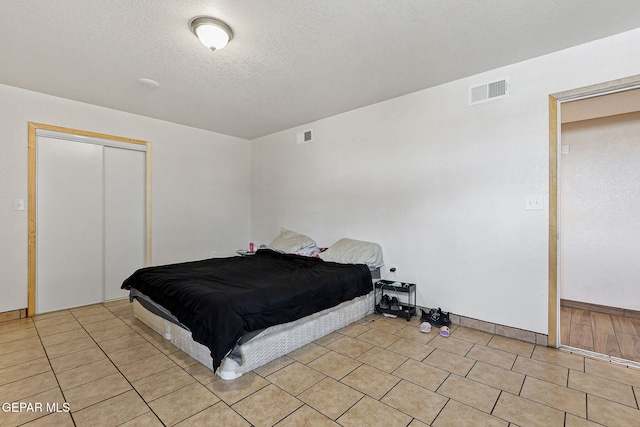702 Thompson Rd, San Elizario, TX 79849 - bedroom with a closet, visible vents, a textured ceiling, and light tile patterned flooring