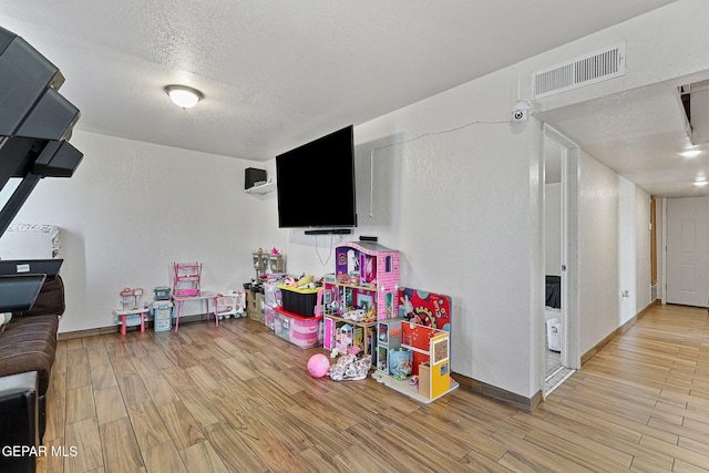 702 Thompson Rd, San Elizario, TX 79849 - game room featuring a textured wall, a textured ceiling, visible vents, light wood finished floors, and baseboards