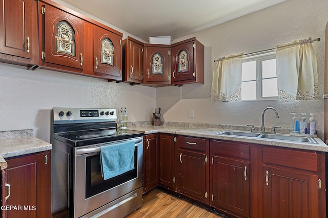 702 Thompson Rd, San Elizario, TX 79849 - kitchen featuring stainless steel electric range oven, a sink, light countertops, a textured wall, and light wood-style floors