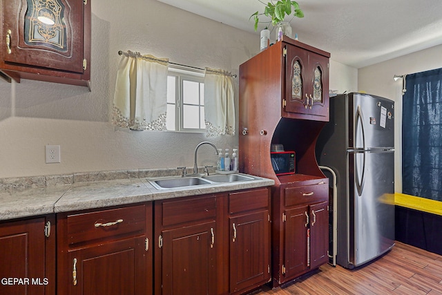 702 Thompson Rd, San Elizario, TX 79849 - kitchen featuring light countertops, freestanding refrigerator, dark brown cabinets, light wood finished floors, and a sink
