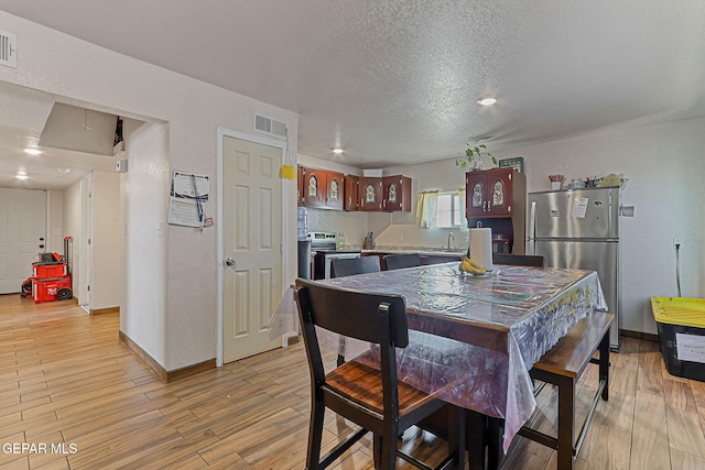 702 Thompson Rd, San Elizario, TX 79849 - dining space featuring baseboards, light wood-style floors, a textured ceiling, and visible vents