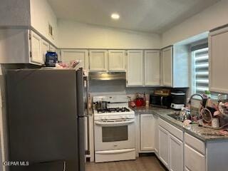 144 Marquita Ln, El Paso, TX 79915 - kitchen featuring freestanding refrigerator, white range with gas stovetop, under cabinet range hood, stainless steel microwave, and a sink