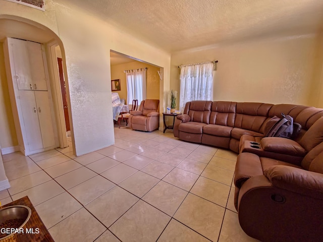 7726 Monterrey Dr, El Paso, TX 79915 - living room with arched walkways, light tile patterned floors, and a textured ceiling