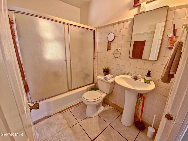 7726 Monterrey Dr, El Paso, TX 79915 - bathroom with tile patterned flooring, toilet, a sink, combined bath / shower with glass door, and tile walls