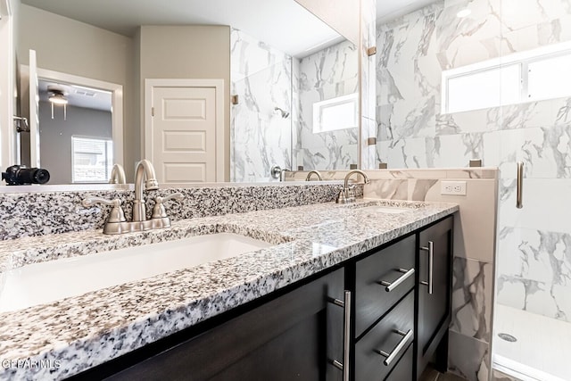 full bathroom with double vanity, a marble finish shower, and a sink