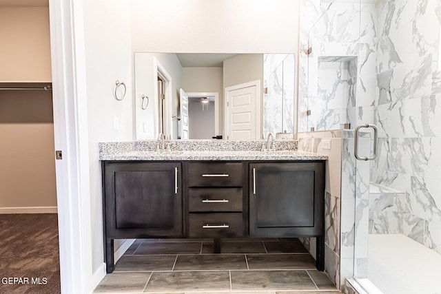 full bathroom featuring a stall shower, double vanity, and a sink