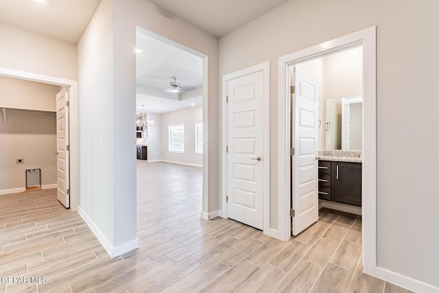 hall featuring baseboards, wood finish floors, and a chandelier