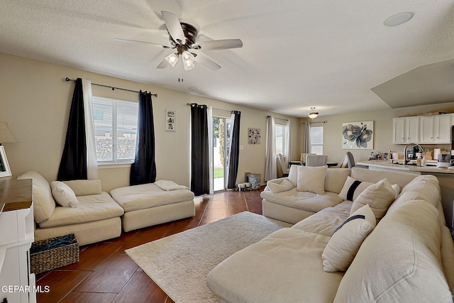 living room featuring a ceiling fan, dark wood-type flooring, and a textured ceiling