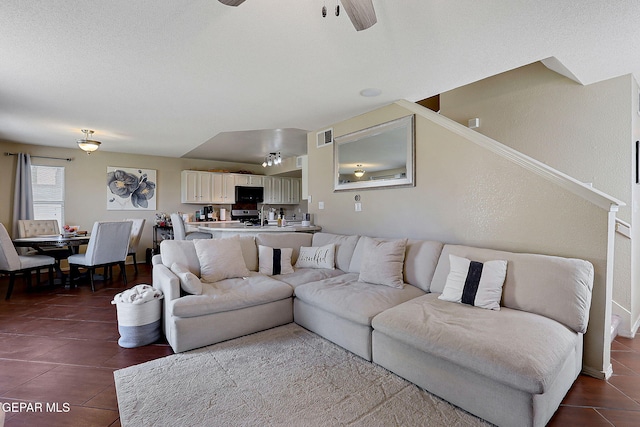 living room with dark tile patterned flooring, a ceiling fan, and stairway