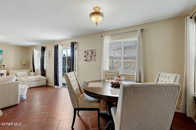 dining space with a textured ceiling and dark tile patterned floors