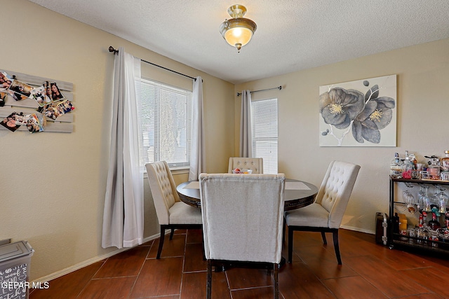 dining space featuring a textured ceiling, dark wood finished floors, and baseboards