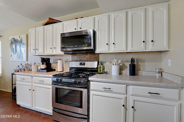 kitchen with appliances with stainless steel finishes, white cabinets, light countertops, decorative backsplash, and a textured ceiling