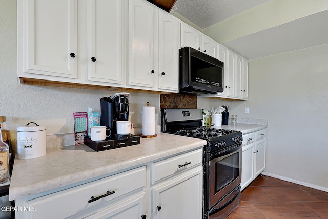 kitchen featuring stainless steel gas range, black microwave, white cabinetry, and light countertops