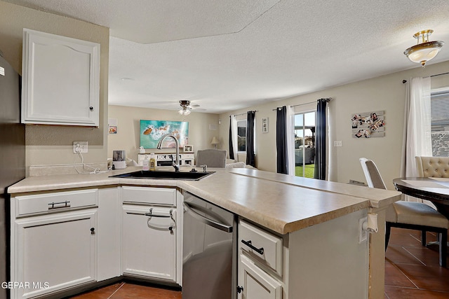 kitchen featuring dark tile patterned flooring, a peninsula, stainless steel dishwasher, a ceiling fan, and white cabinets