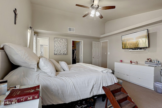 carpeted bedroom with a walk in closet, a ceiling fan, and lofted ceiling