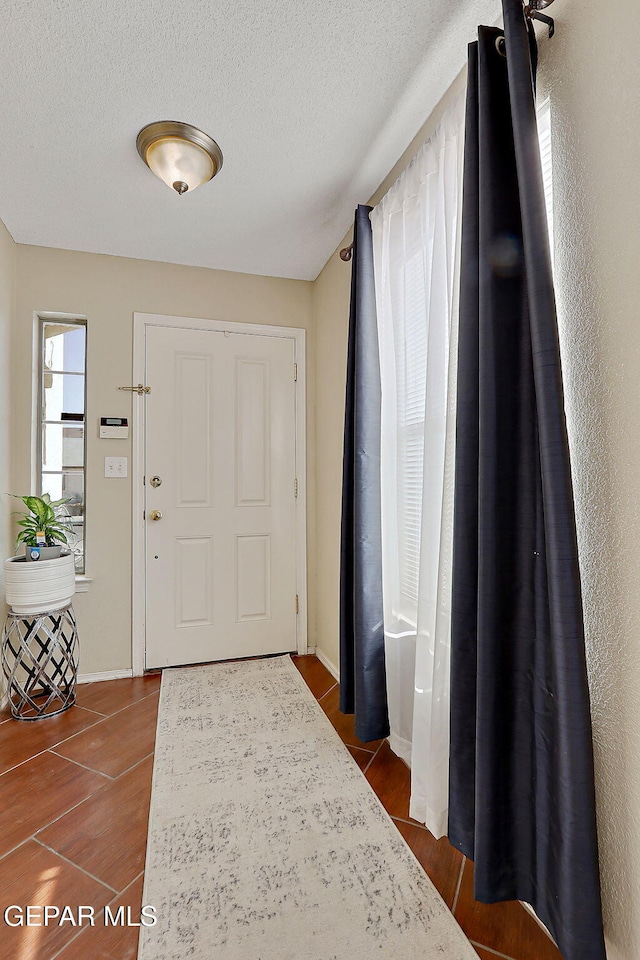 entrance foyer featuring dark wood-type flooring, a textured ceiling, and baseboards
