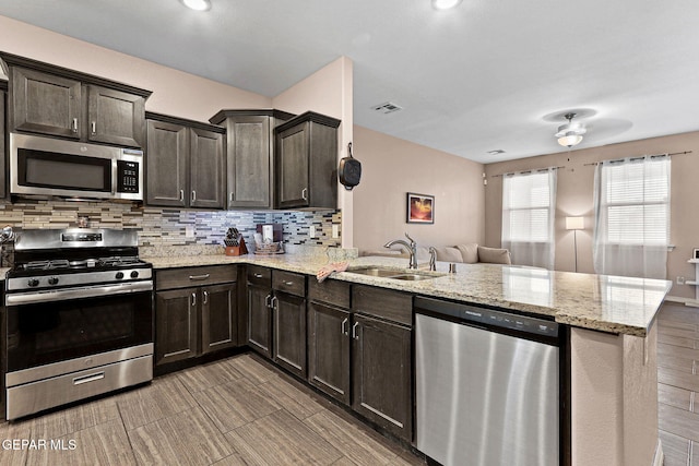14439 Eastbrook Dr, El Paso, TX 79938 - kitchen featuring a sink, appliances with stainless steel finishes, a peninsula, dark brown cabinets, and decorative backsplash