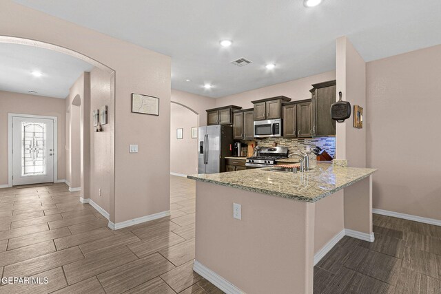 14439 Eastbrook Dr, El Paso, TX 79938 - kitchen with light stone counters, wood tiled floor, appliances with stainless steel finishes, arched walkways, and a sink