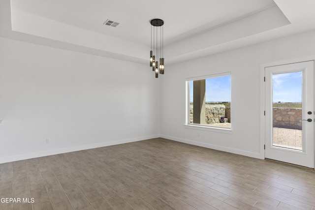 unfurnished room featuring a tray ceiling, visible vents, and a chandelier