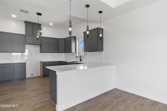 kitchen featuring a peninsula, visible vents, wood finished floors, and a sink