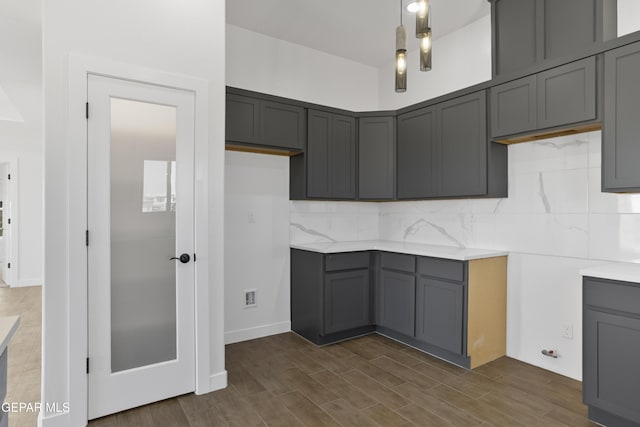 kitchen featuring tasteful backsplash, gray cabinetry, and dark wood-type flooring