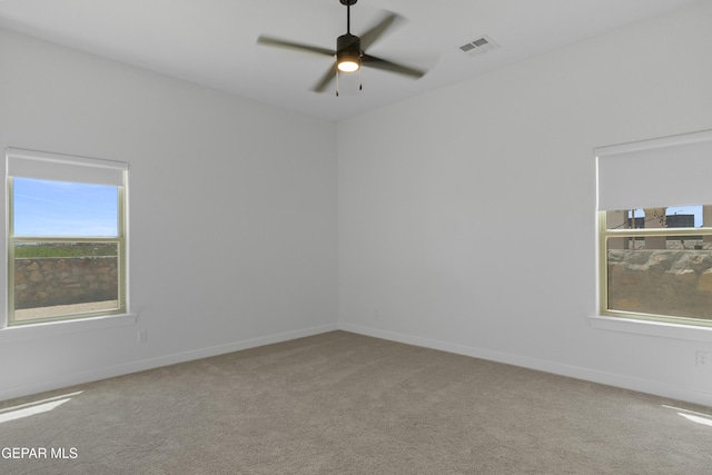 carpeted empty room with a ceiling fan, baseboards, and visible vents