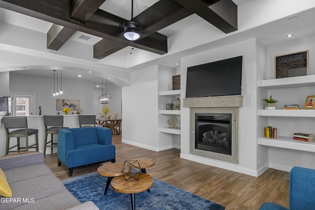 living area with a glass covered fireplace, baseboards, built in features, and wood finished floors