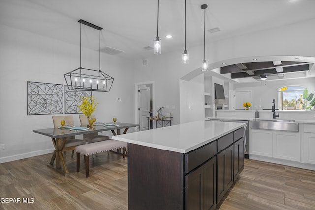 kitchen featuring recessed lighting, light countertops, coffered ceiling, a sink, and wood finished floors