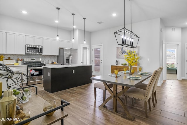 kitchen with visible vents, a center island, appliances with stainless steel finishes, light countertops, and decorative backsplash