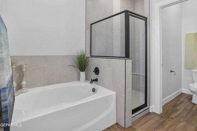 bathroom featuring a garden tub, a stall shower, and wood finished floors