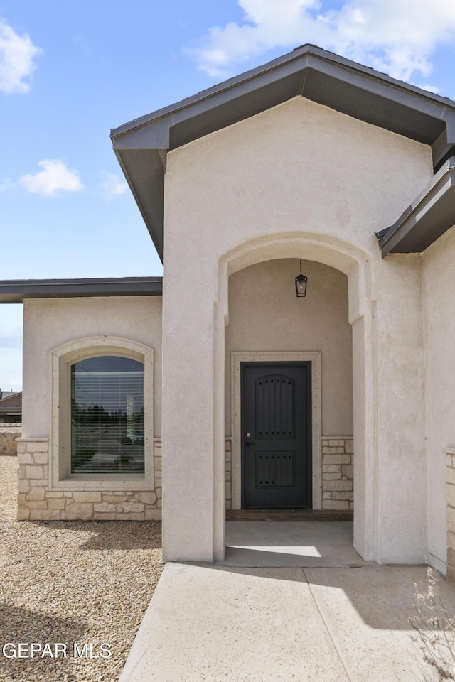 doorway to property featuring stucco siding and stone siding
