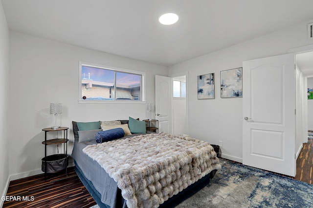 bedroom with dark wood-type flooring and baseboards