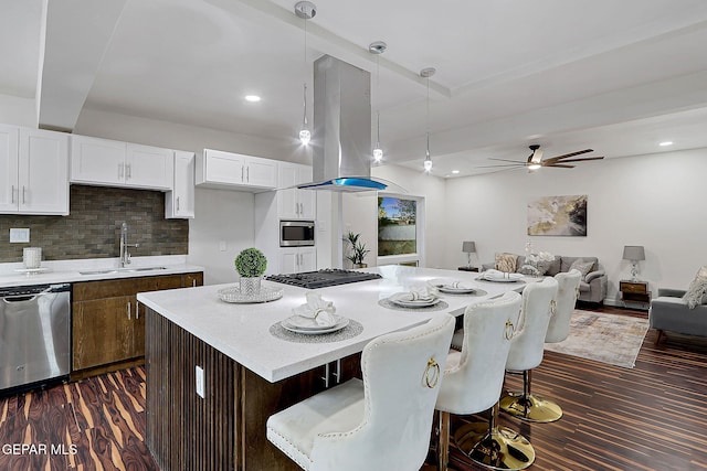 kitchen with island exhaust hood, white cabinetry, a ceiling fan, stainless steel appliances, and a sink