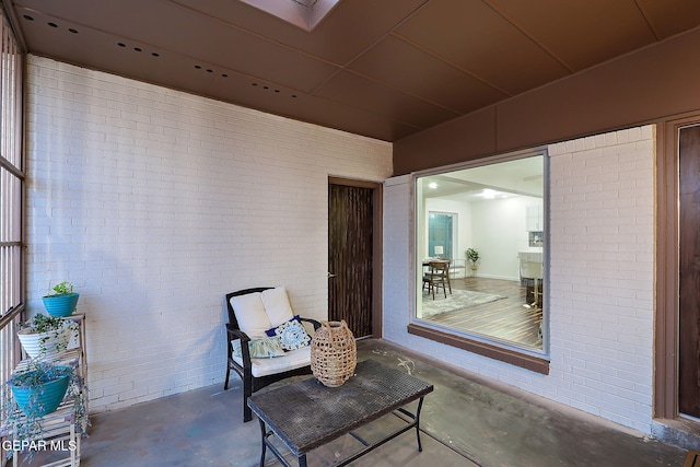 living area featuring brick wall and concrete floors