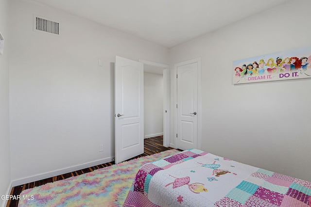 bedroom featuring visible vents, baseboards, and wood finished floors