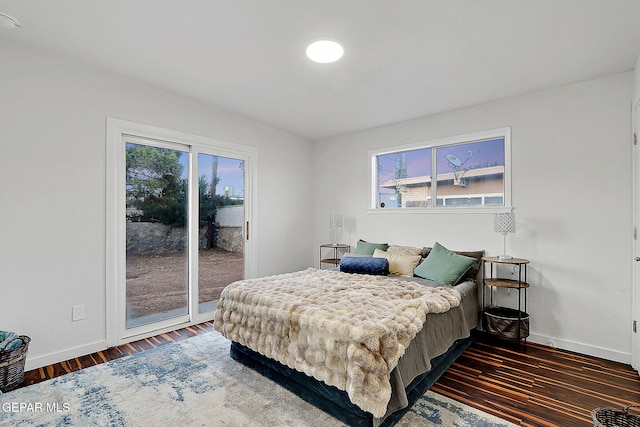 bedroom featuring access to exterior, wood finished floors, baseboards, and multiple windows