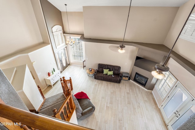 400 Rio Fango, El Paso, TX 79932 - living room featuring wood finished floors, a high ceiling, a glass covered fireplace, and ceiling fan with notable chandelier