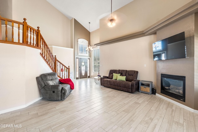 400 Rio Fango, El Paso, TX 79932 - living room featuring high vaulted ceiling, a glass covered fireplace, stairway, a chandelier, and wood finished floors