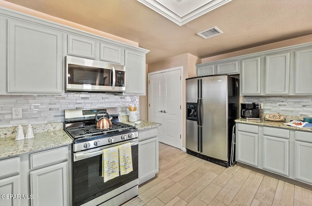 400 Rio Fango, El Paso, TX 79932 - kitchen with tasteful backsplash, light stone counters, light wood-style floors, visible vents, and stainless steel appliances