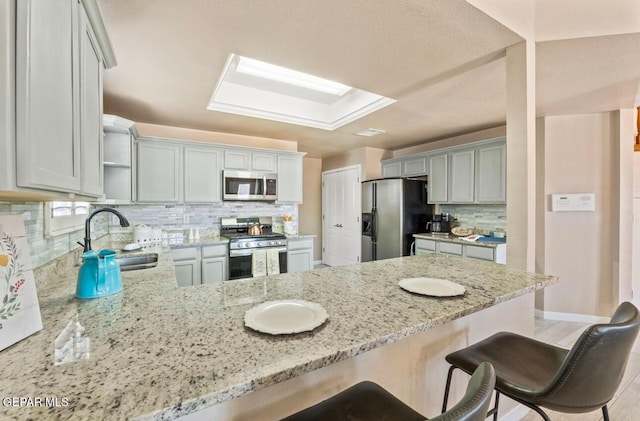 400 Rio Fango, El Paso, TX 79932 - kitchen featuring tasteful backsplash, light stone counters, a peninsula, appliances with stainless steel finishes, and a sink