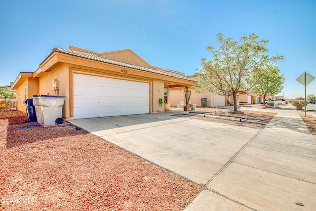 view of front of home featuring a tiled roof, an attached garage, driveway, and stucco siding